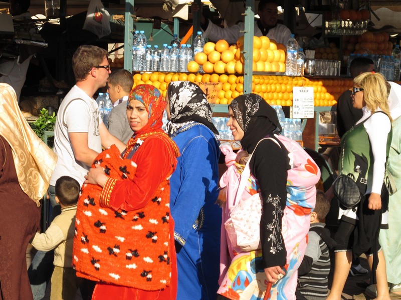 Morocco, Marrakesh. Women and children with fresh juice on background
