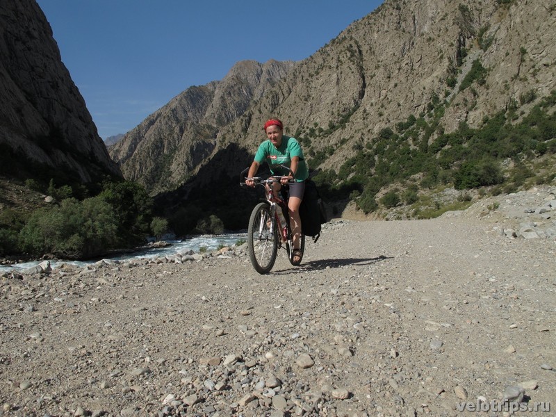 Tajikistan, Rufigar. Woman on bicycle on road